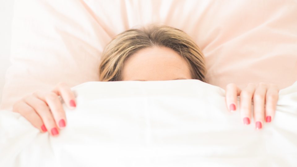 Mujer acostada en la cama, despierta tras una noche de sueño no reparador