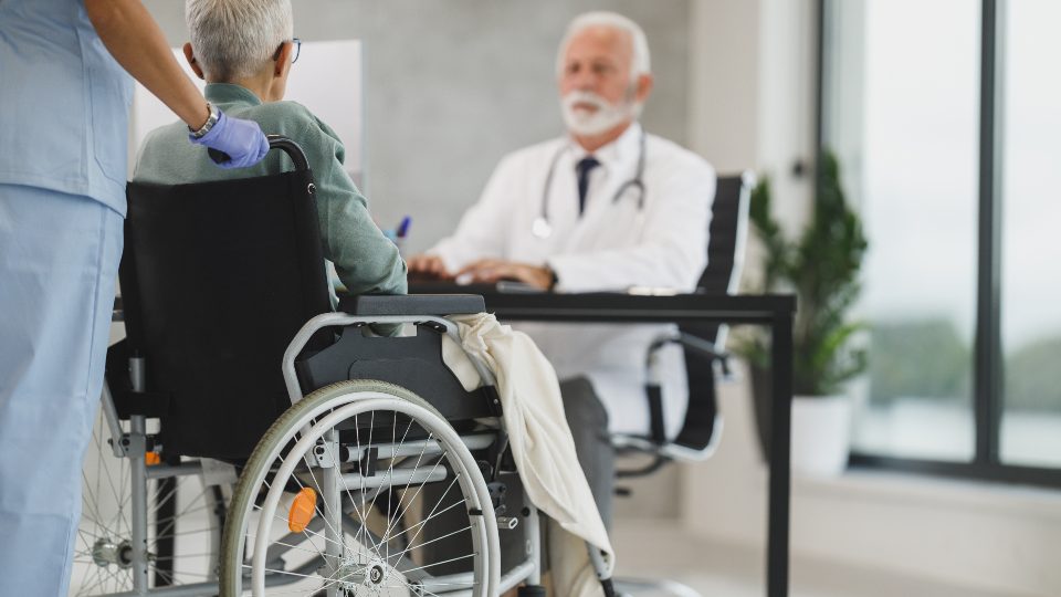 Médico acompañando a un paciente en silla de ruedas durante su recuperación